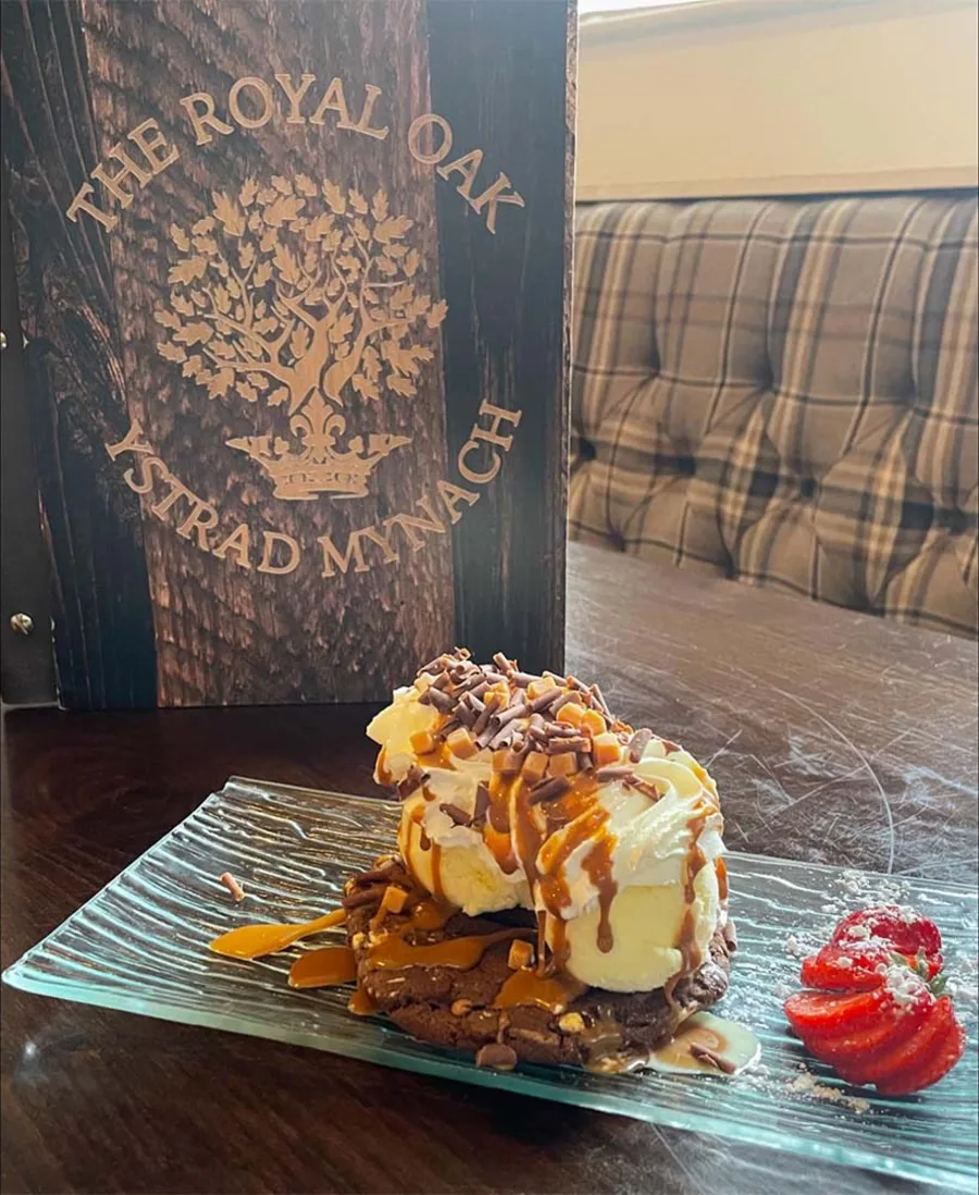 A dessert served on the pub's own wooden board, branded with an oak tree and Ystrad Mynach.